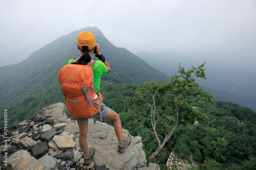 Obraz premium woman hiker taking photo on the top of mountain
