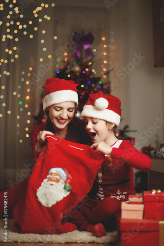 Cute girl and her mother on a Christmas/New Year’s Eve, opening presents 