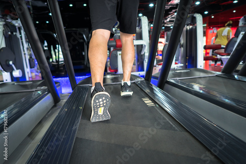 Gym treadmill closeup with man legs running. Concept for exercising, fitness and healthy lifestyle