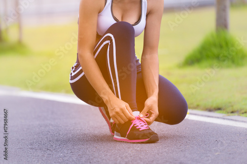 Young woman runner tying shoelaces with copy space,in the park, healthy lifestyle and sport concepts