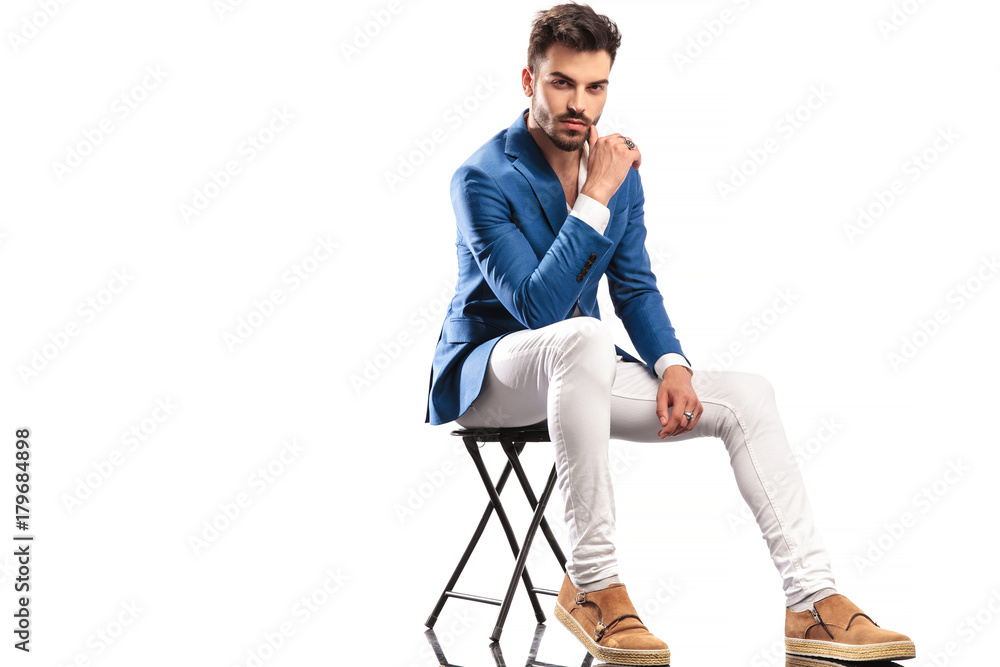 seated fashion man touching his face with finger seated fashion man touching his face with finger