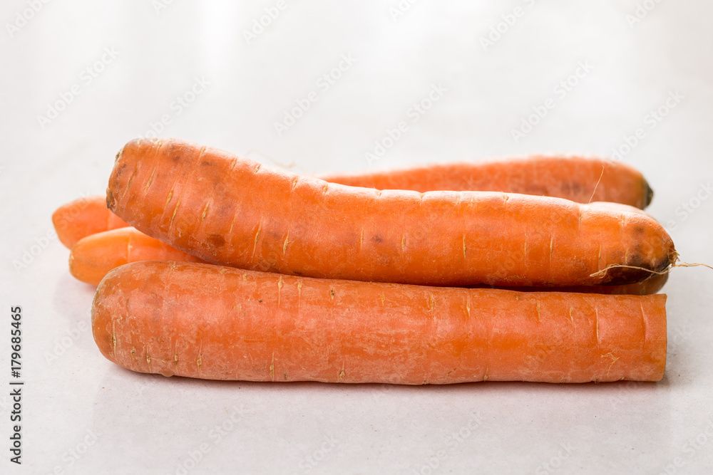 Fresh raw dirty carrot from the garden on the white marble background Fresh raw dirty carrot from the garden on the white marble background