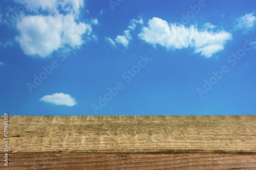 old wooden table on a background of blue sky with clouds
