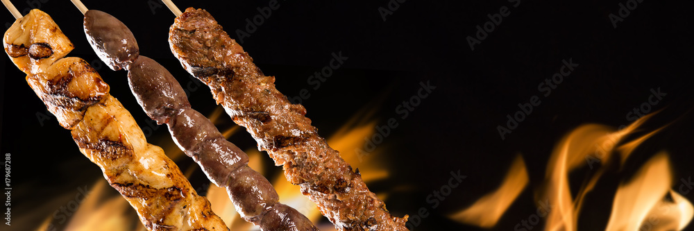 Assorted steak skewers on a fire background