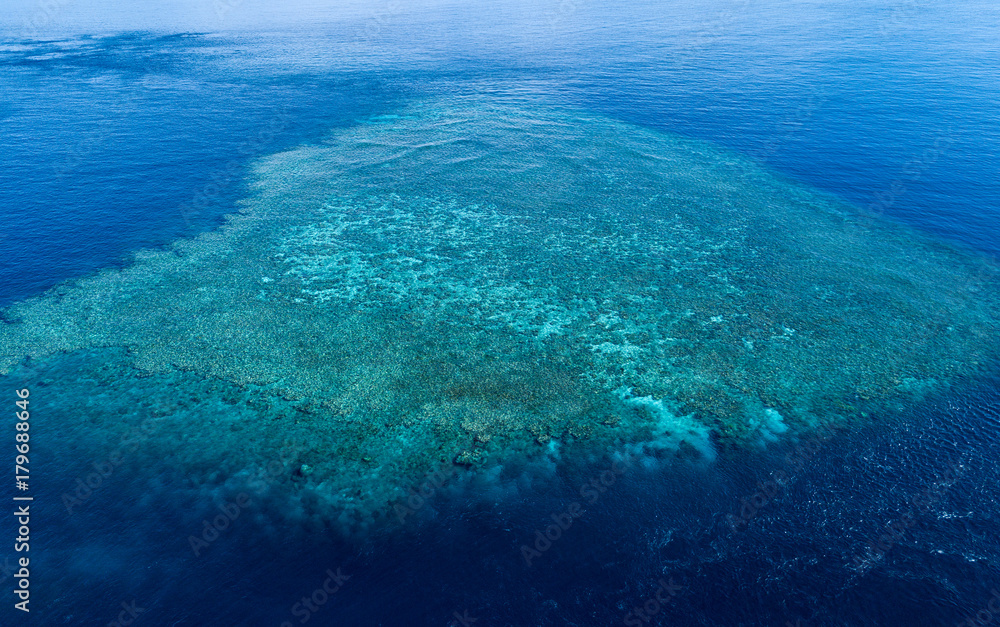 Aerial view of the Great Barrier Reef with a wide reef structure at low tide. The Great Barrier Reef is in Queensland, Australia.