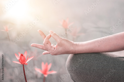 Woman yoga practicing and meditating by the red lotus lake background, fillter image