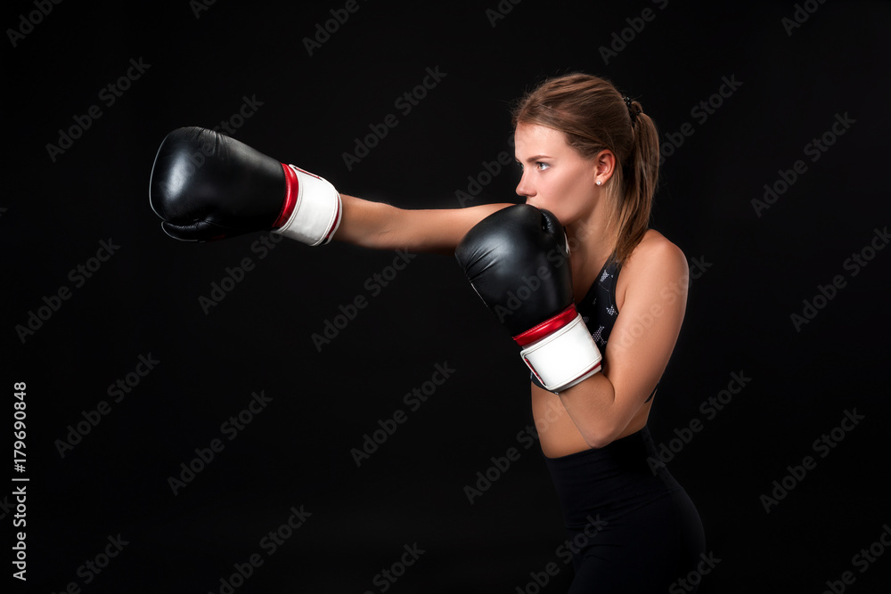 Beautiful female athlete in boxing gloves, in the studio on a black background.