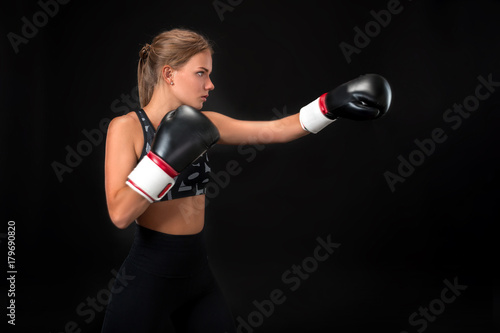 Beautiful female athlete in boxing gloves, in the studio on a black background. © nazarovsergey