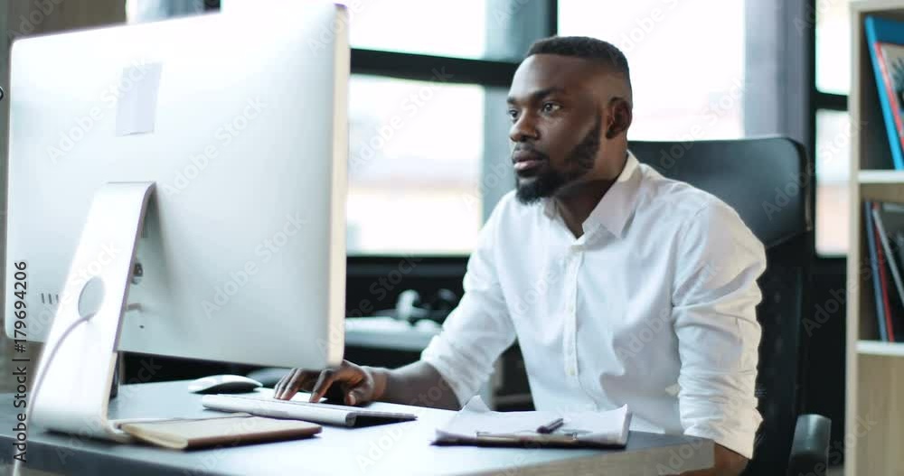 Young black man working use computer in office smiling technology african american businessman casual communication entrepreneur male successful person portrait smart business Slow Motion Shot Young black man working use computer in office smiling technology african american businessman casual communication entrepreneur male successful person portrait smart business Slow Motion Shot