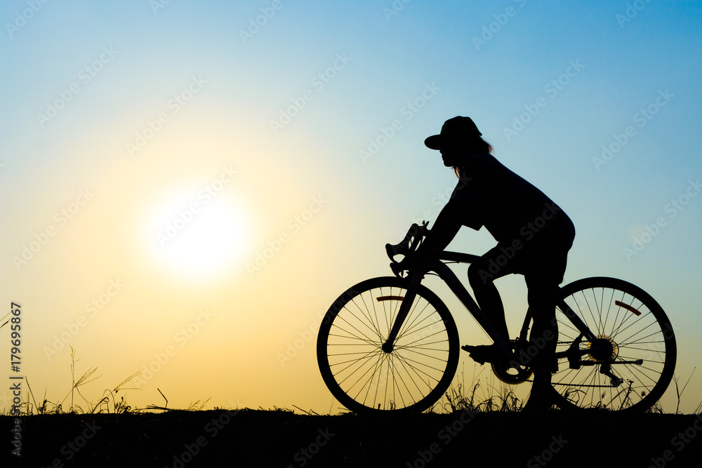 Fototapeta premium Woman cyclist silhouette riding a bicycle at sunset