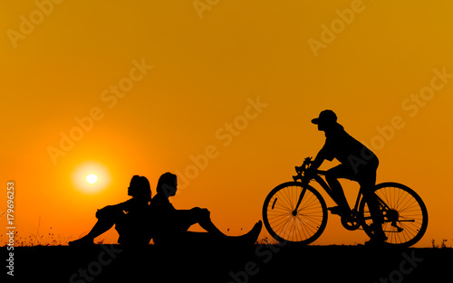 silhouette of young woman cyclist and jumping on sunset sky with stop on the prairie at yellow evening horizon sea yellow sunset heaven background Outdoor.