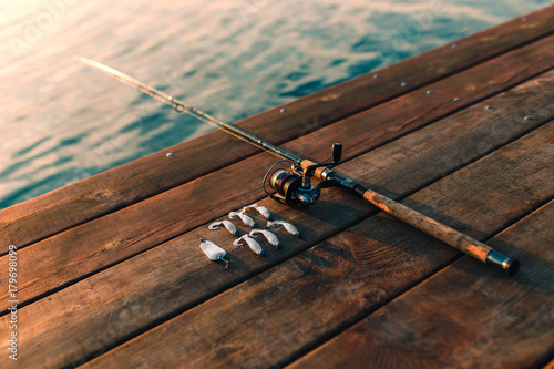 Fotografiet Fishing rod and lures on a wooden dock.