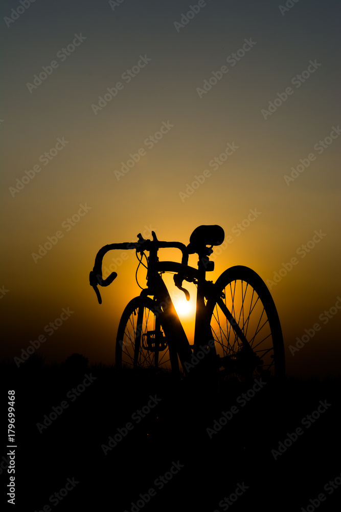 a silhouette of a bicycle with the sun setting behind it. a silhouette of a bicycle with the sun setting behind it.
