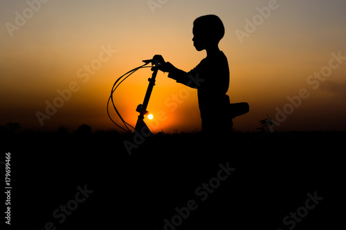 Bicycle silhouettes with a boy on sunset, standing.