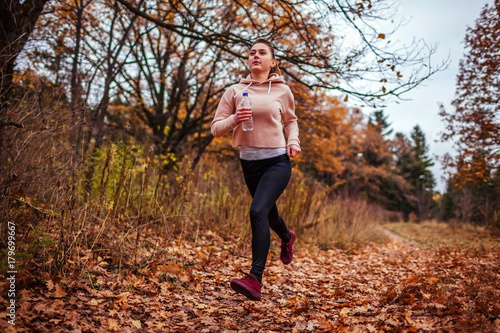 Young woman running in autumn forest