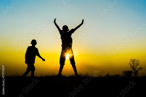 Silhouette of children jumping on sunset.