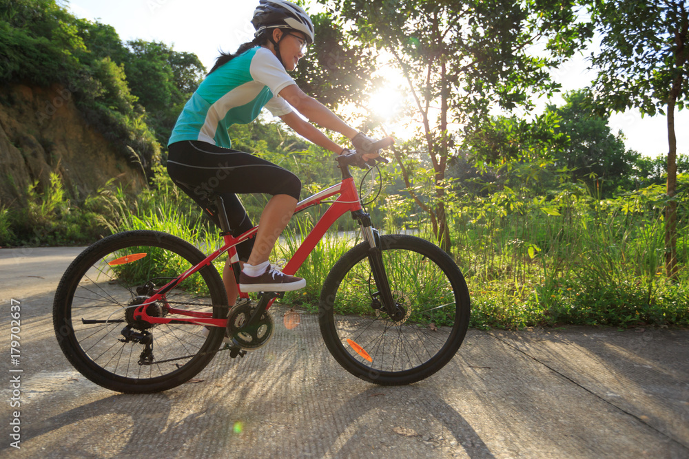 woman cyclist cycling on sunrise forest trail woman cyclist cycling on sunrise forest trail
