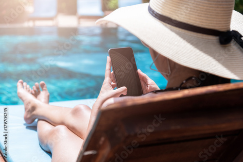 Beautiful girl woman happy use smartphone relaxing near swimming pool © sorapop