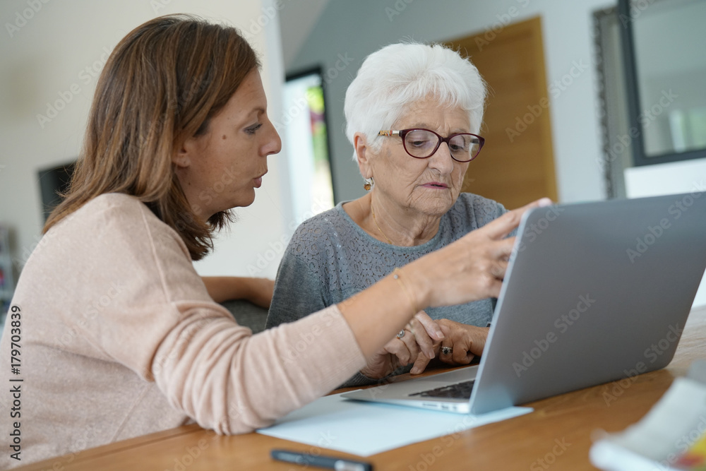 Elderly woman using laptop with help of homecarer Elderly woman using laptop with help of homecarer