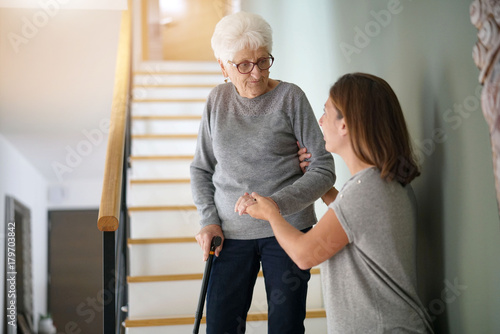 Homecare helping elderly woman going down the stairs photo