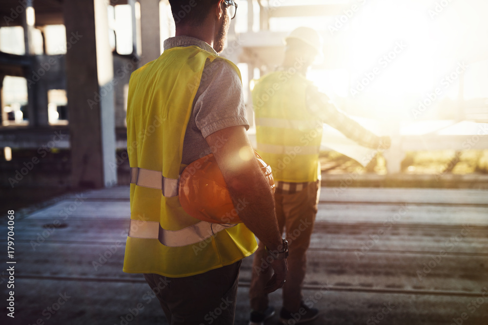 Portrait of construction engineers working on building site - obrazy, fototapety, plakaty 