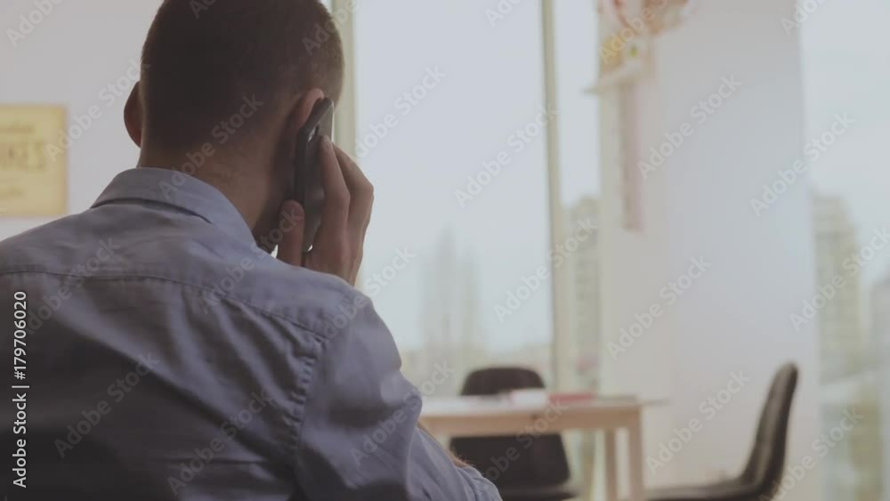 the man receives an incoming call, phone conversation in a room interior, a view from a back the man receives an incoming call, phone conversation in a room interior, a view from a back