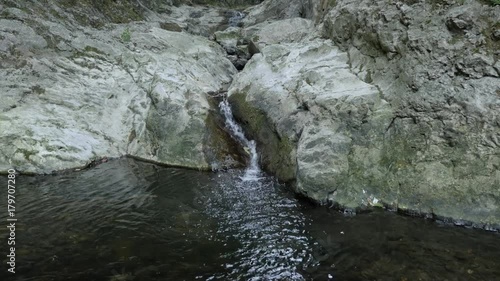 Beautiful water flow cascades footage - Spring under natural stone bridge photo