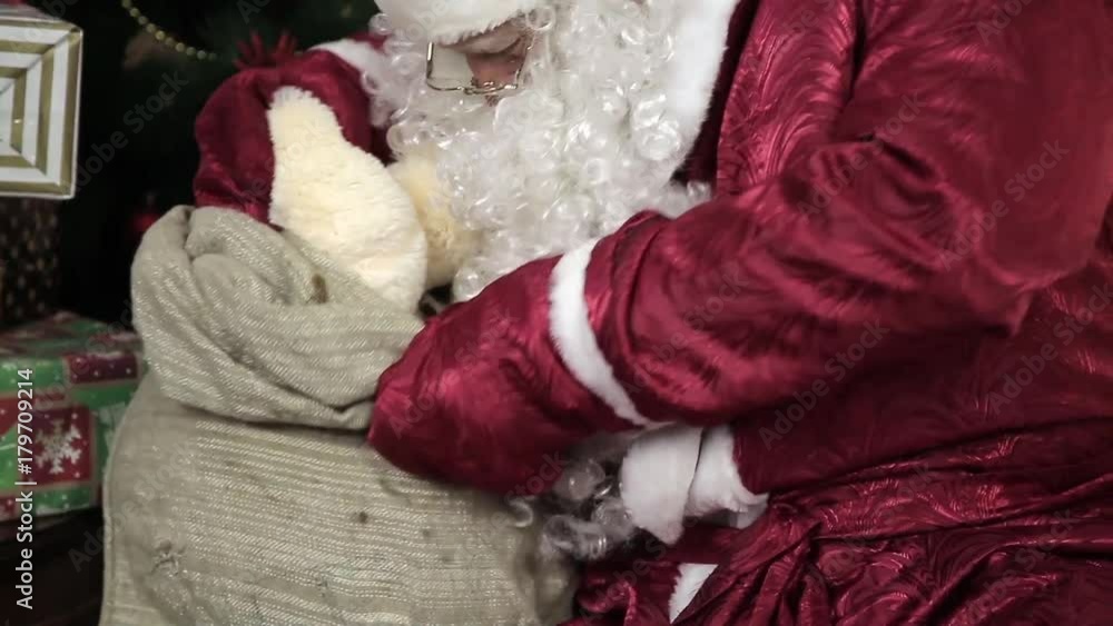 Santa Claus gets gifts from the bag. Merry Santa Claus gets a gift from a big gray bag - a soft toy. Santa Claus gets gifts from the bag. Merry Santa Claus gets a gift from a big gray bag - a soft toy.