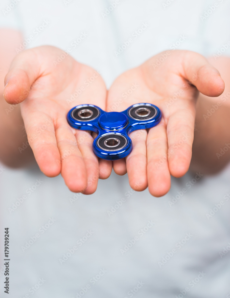 Fototapeta premium young man playing with a fidget spinner, focus on hand.