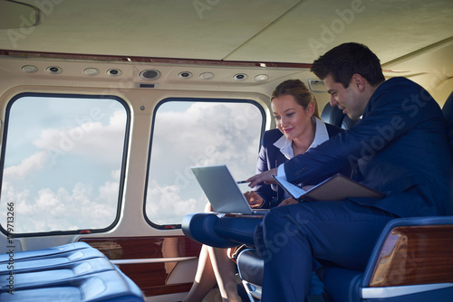 Businessman And Businesswoman Working On Laptop In Helicopter Cabin