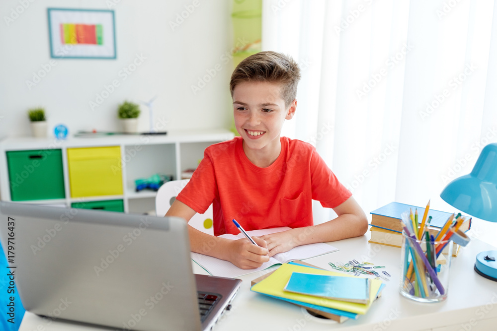 student boy with laptop writing to notebook student boy with laptop writing to notebook