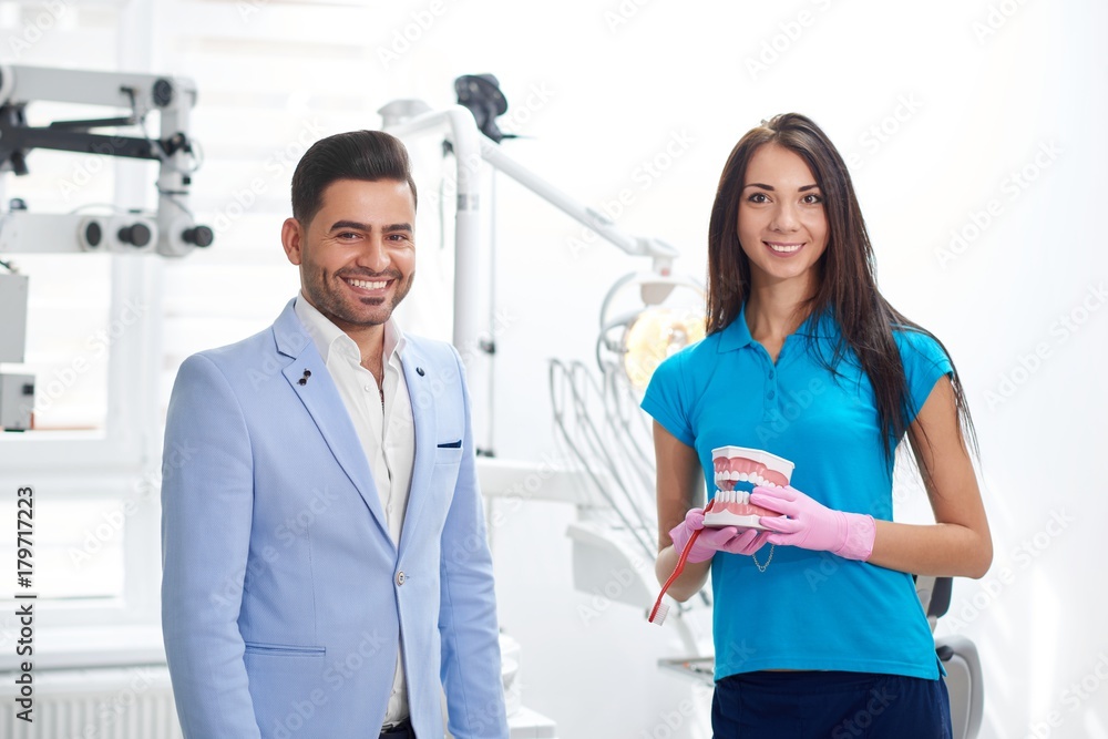Cheerful handsome male patient smiling posing with his dentist at the clinic service friendly helpful specialist medicine staff healthcare appointment professionalism occupation job people. Cheerful handsome male patient smiling posing with his dentist at the clinic service friendly helpful specialist medicine staff healthcare appointment professionalism occupation job people.