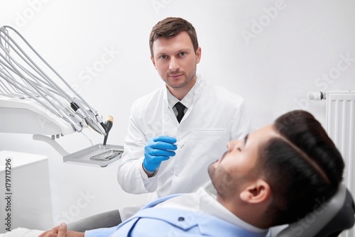 Shot of a mature male dentist at work preparing to examine teeth of his male patient clinic office hospital dentistry professionalism healthcare medicine examination checkup dental concept. photo