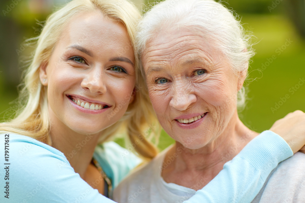 daughter with senior mother hugging on park bench