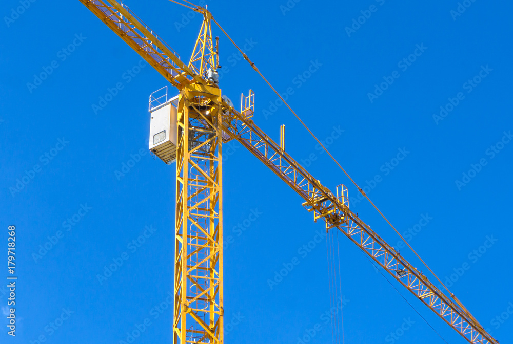 Yellow construction tower crane against blue sky Yellow construction tower crane against blue sky
