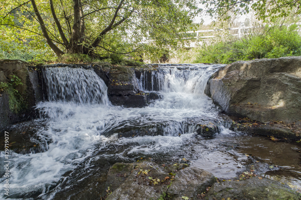 Obraz premium Waterfall in a river between rocks and trees 