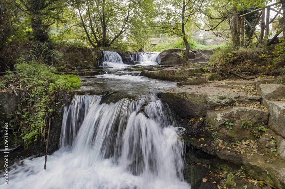 Waterfall in a river between rocks and trees Waterfall in a river between rocks and trees
