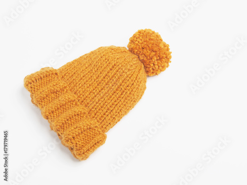 Mustard knit beanie hat with big pom pom isolated on white background. Copy space. Flat lay. Top view