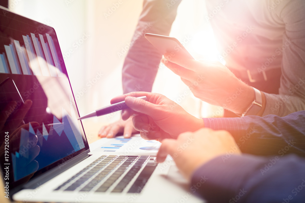 Naklejka premium Two colleagues working on new global financial strategy plan using laptop and smartphone.Modern business team innovation concept.Project meeting at office with virtual graph and chart data interface