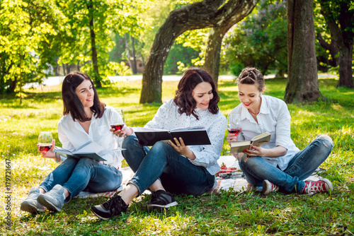 Young beautiful girls with glass of red wine and books in the park. © romaset