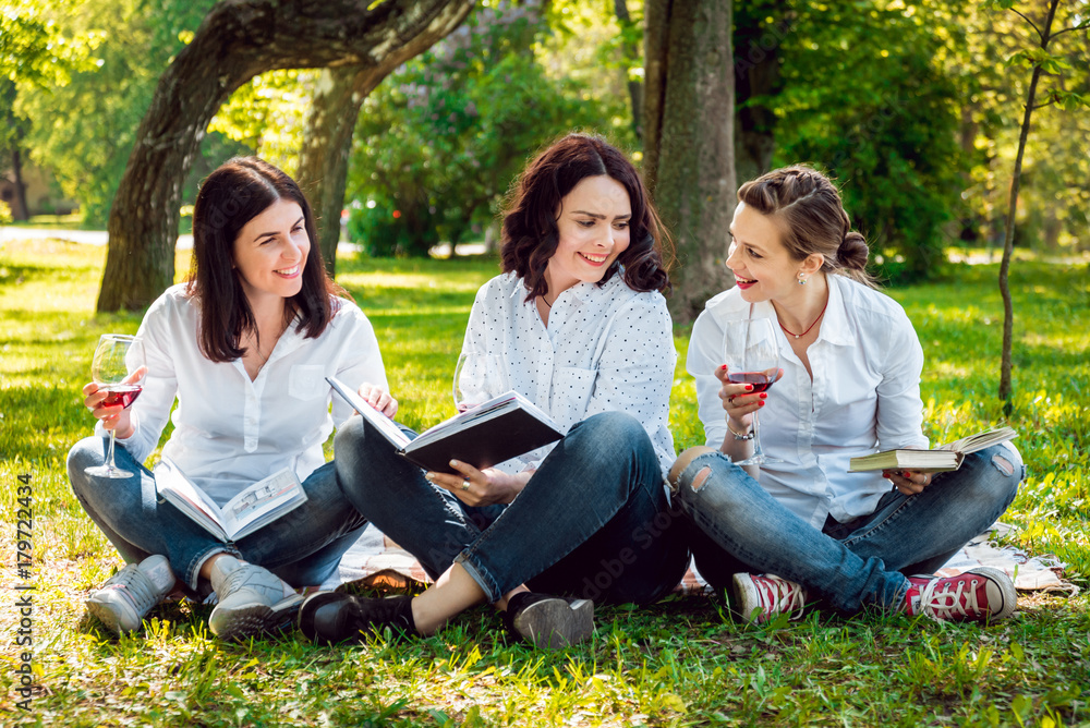 Young beautiful girls with glass of red wine and books in the park. Young beautiful girls with glass of red wine and books in the park.