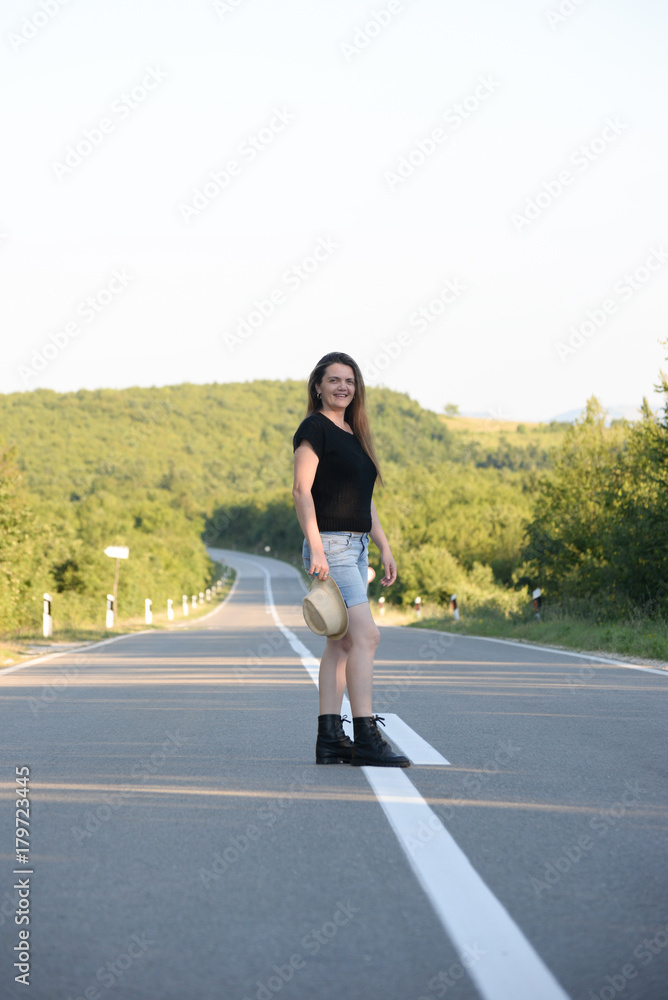 Woman Walking on the road in mountains at sunset. Lonely middle aged woman on the road Woman Walking on the road in mountains at sunset. Lonely middle aged woman on the road