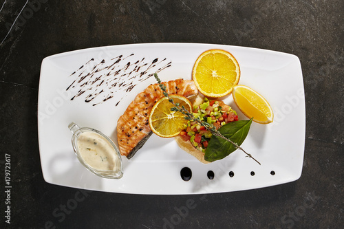 Salmon steak with vegetable salsa and blue cheese sauce with orange slices and greens