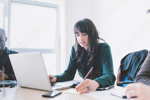Young beautiful caucasian businesswoman sitting on a desk  using computer - technology  working  business concept