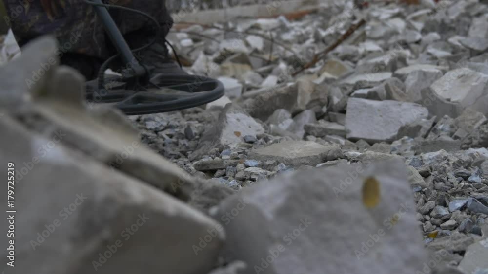 The soldier works with a mine detector in the ruins of houses in search of mines and explosives
