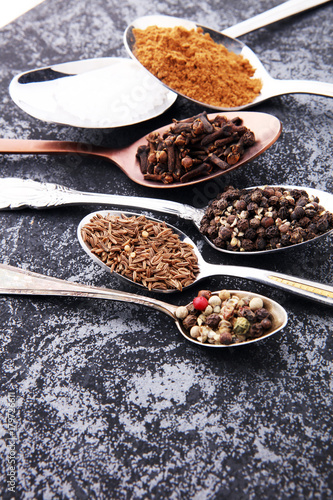 Various spices and spoons on dark table.