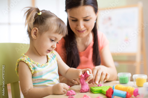 Mother and kid daughter at home molded from clay and play together. Concept of preschool or home education.