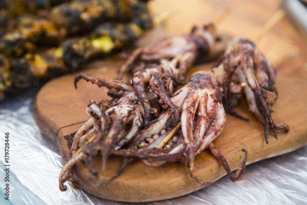 Grilled octopus on a wooden board at a street market Grilled octopus on a wooden board at a street market