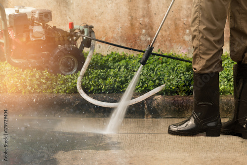 High pressure deep cleaning..Worker cleaning driveway with gasoline high pressure washer ,professional cleaning services.