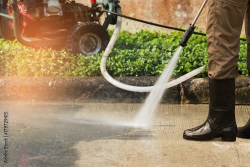 High pressure deep cleaning. .Worker cleaning driveway with gasoline high pressure washer ,professional cleaning services.